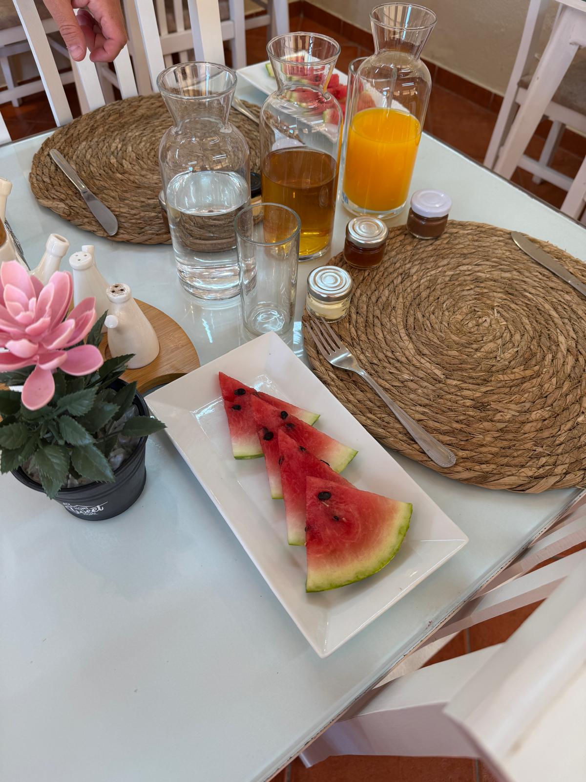 Breakfast table with fresh watermelon, orange juice and homemade jams at Hotel Bebej Tradicional