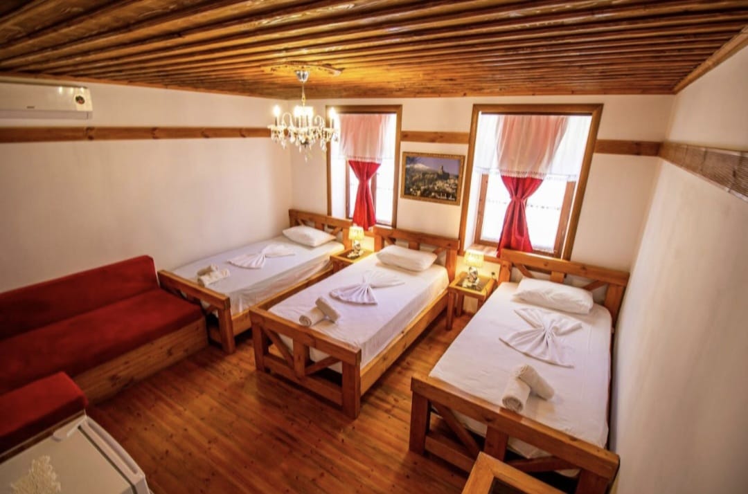 Twin room with red accents and traditional wood ceiling